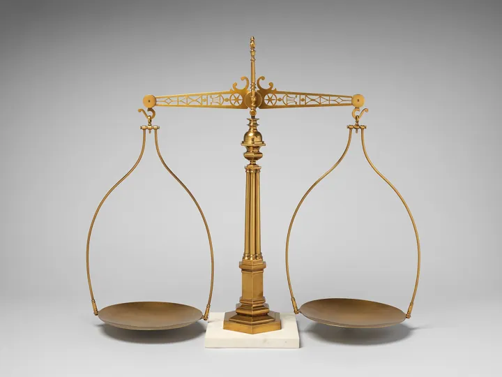 Photo d’origine : Une balance à plateaux en laiton sur un socle de marbre, plateaux vides en équilibre.