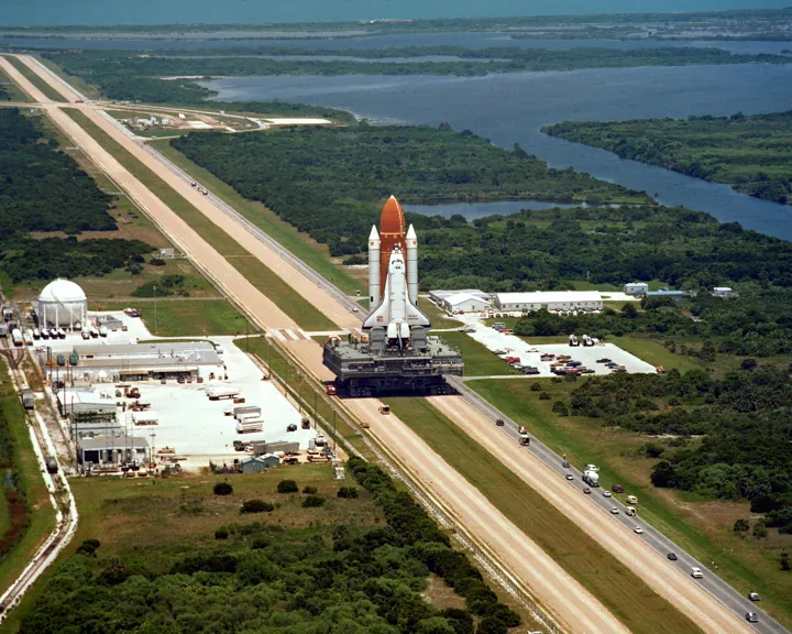 Photo d’origine : La navette spatiale Challenger transportée sur son chenillard vers la rampe de lancement, au milieu des marais de Floride.