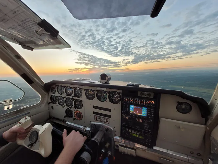 Photo d’origine : Tableau de bord d'un petit avion : cadrans et écran de navigation à lire d'un coup d'œil, au-dessus d'un ciel de crépuscule.
