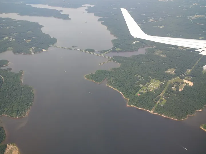 Photo d’origine : Vue aérienne d’un grand lac aux rives boisées, traversé par une chaussée.