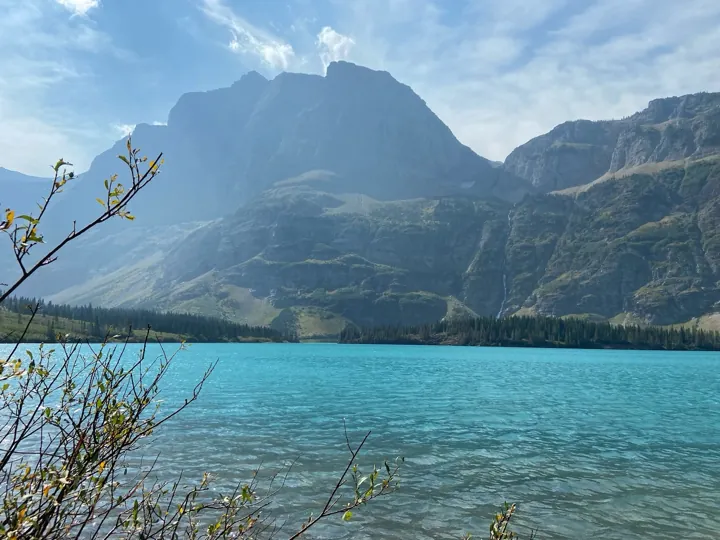 Photo d’origine : Lac d’un bleu turquoise au pied d’un massif rocheux de montagne.