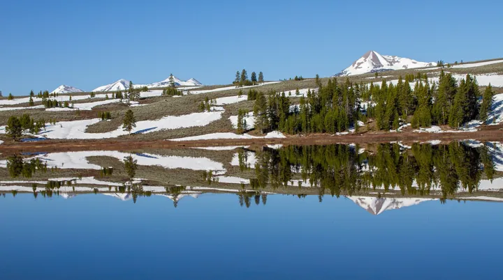 Photo d’origine : Montagnes et forêt se reflétant dans l'eau immobile d'un lac