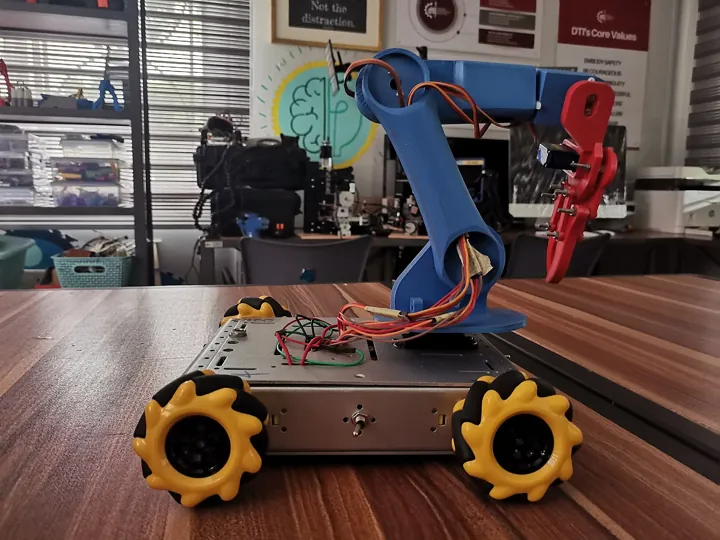 Photo d’origine : Un petit robot à roues omnidirectionnelles équipé d'un bras articulé
