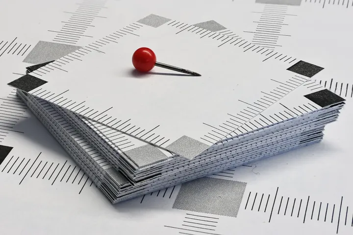 Photo d’origine : Punaise rouge posée sur une pile de cartes de papier.