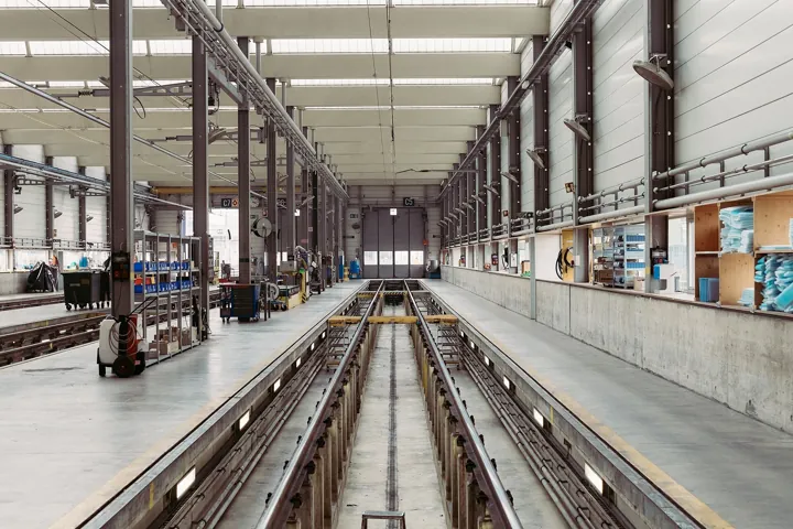 Photo d’origine : Nef d’un atelier d’entretien ferroviaire, avec sa fosse et ses rails, ses étagères et ses rangements alignés.