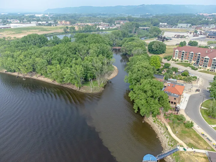 Photo d’origine : Vue aérienne d’une petite rivière qui se jette dans un grand fleuve entre des rives boisées.