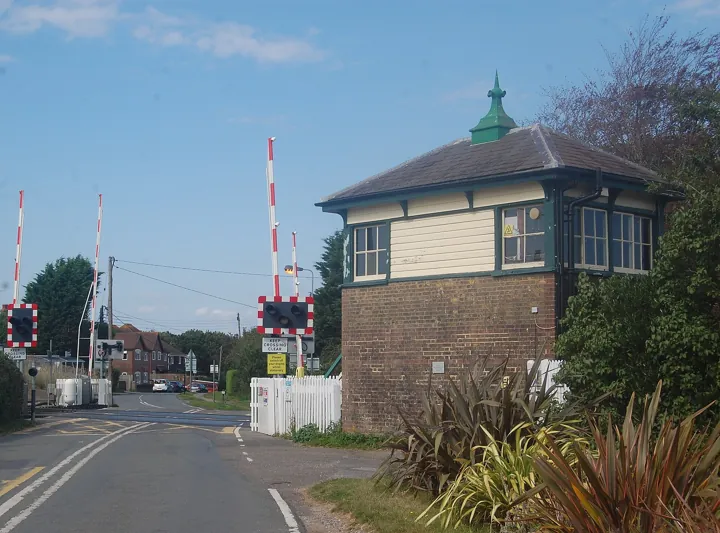 Photo d’origine : Poste d'aiguillage ferroviaire à côté d'un passage à niveau : un point de supervision du trafic.