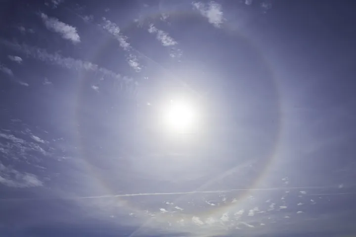 Photo d’origine : Un halo lumineux en anneau autour du soleil dans un ciel bleu.