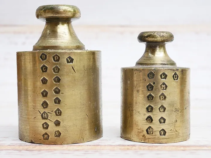 Photo d’origine : Deux poids en laiton couverts de poinçons de vérification : la conformité attestée avant l'usage